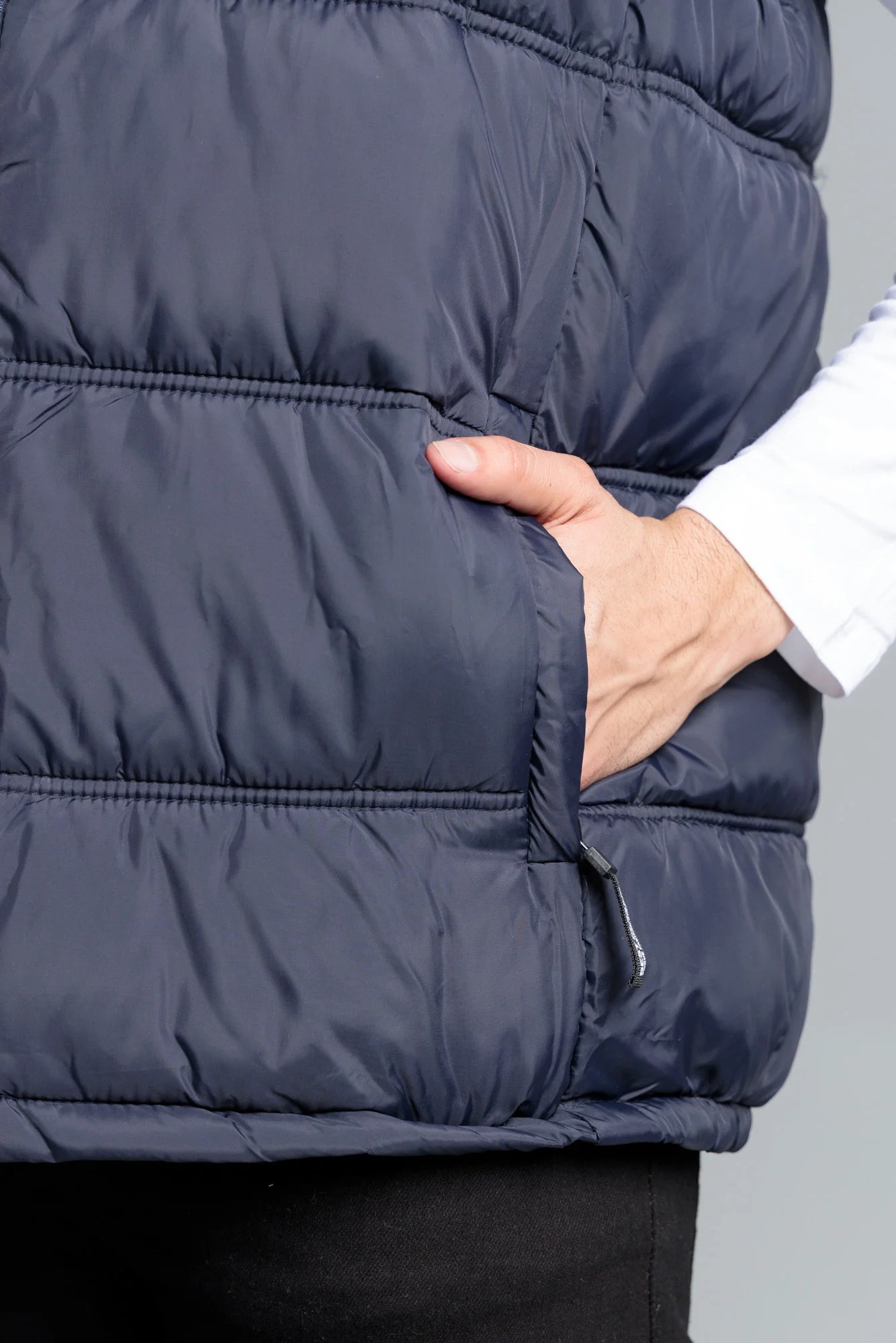 Navy puffer vest worn by a person with a neutral background