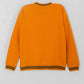 Orange sweater with black trim on a light gray background