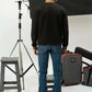 Person standing in a studio with camera equipment and lighting setup