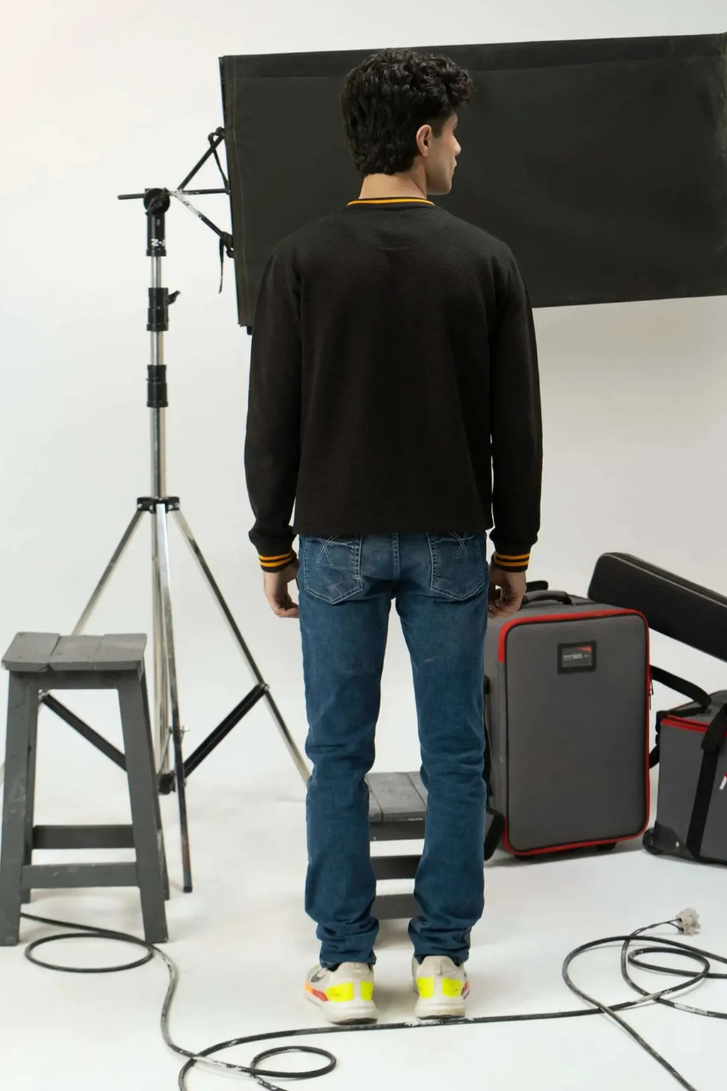 Person standing in a studio with camera equipment and lighting setup