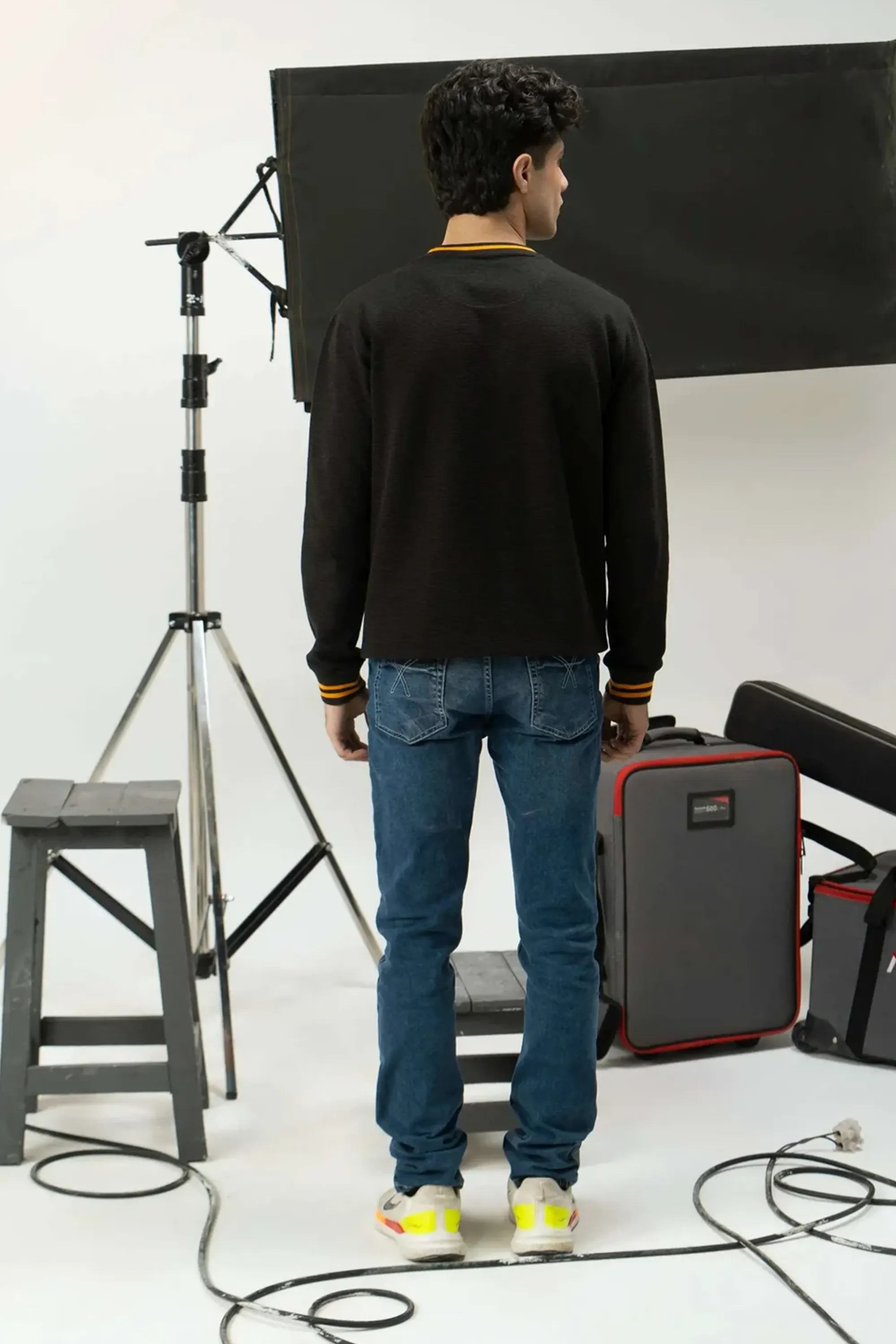 Person standing in a studio with camera equipment and lighting setup
