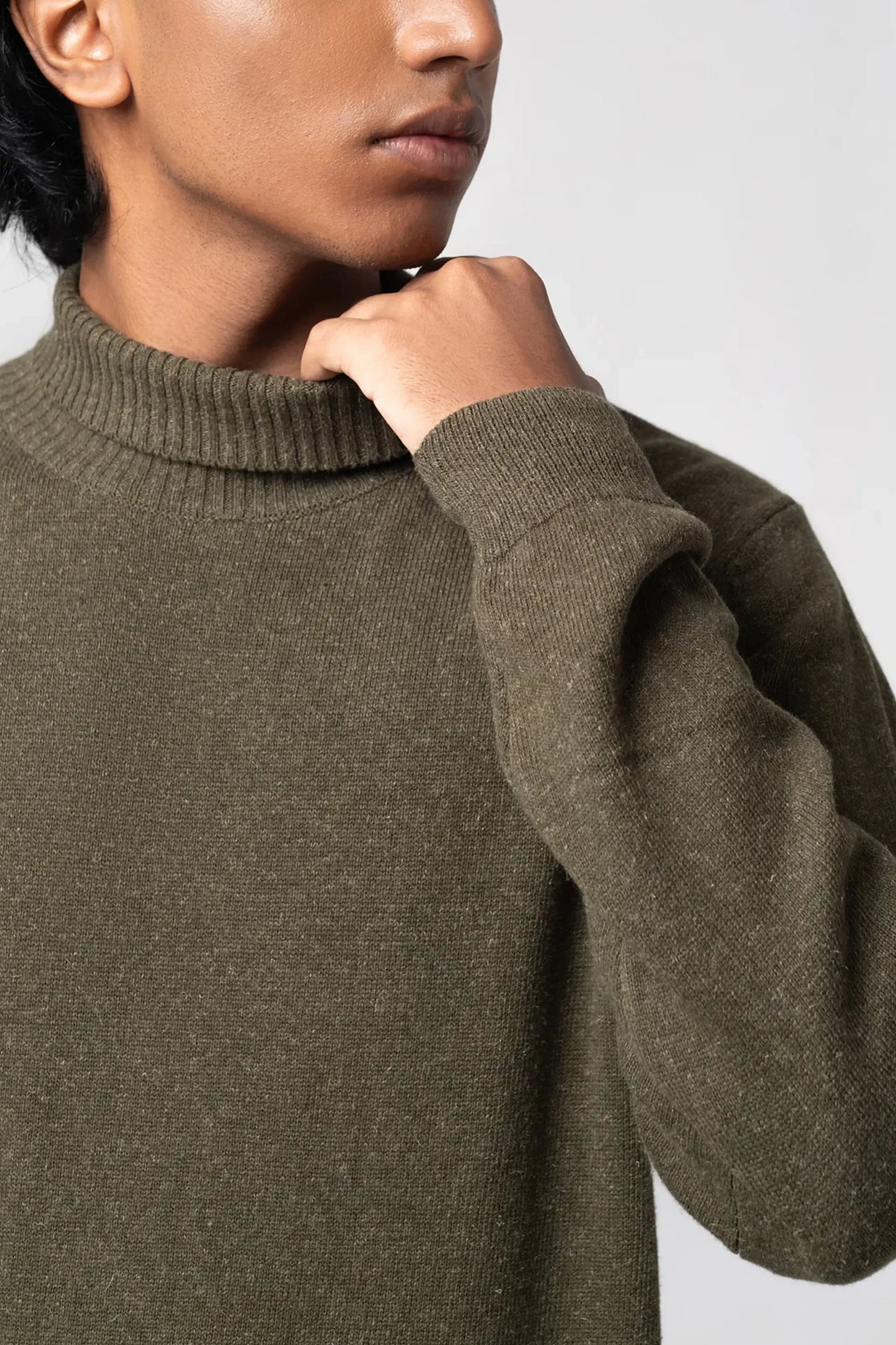 Person wearing a brown sweater against a light background