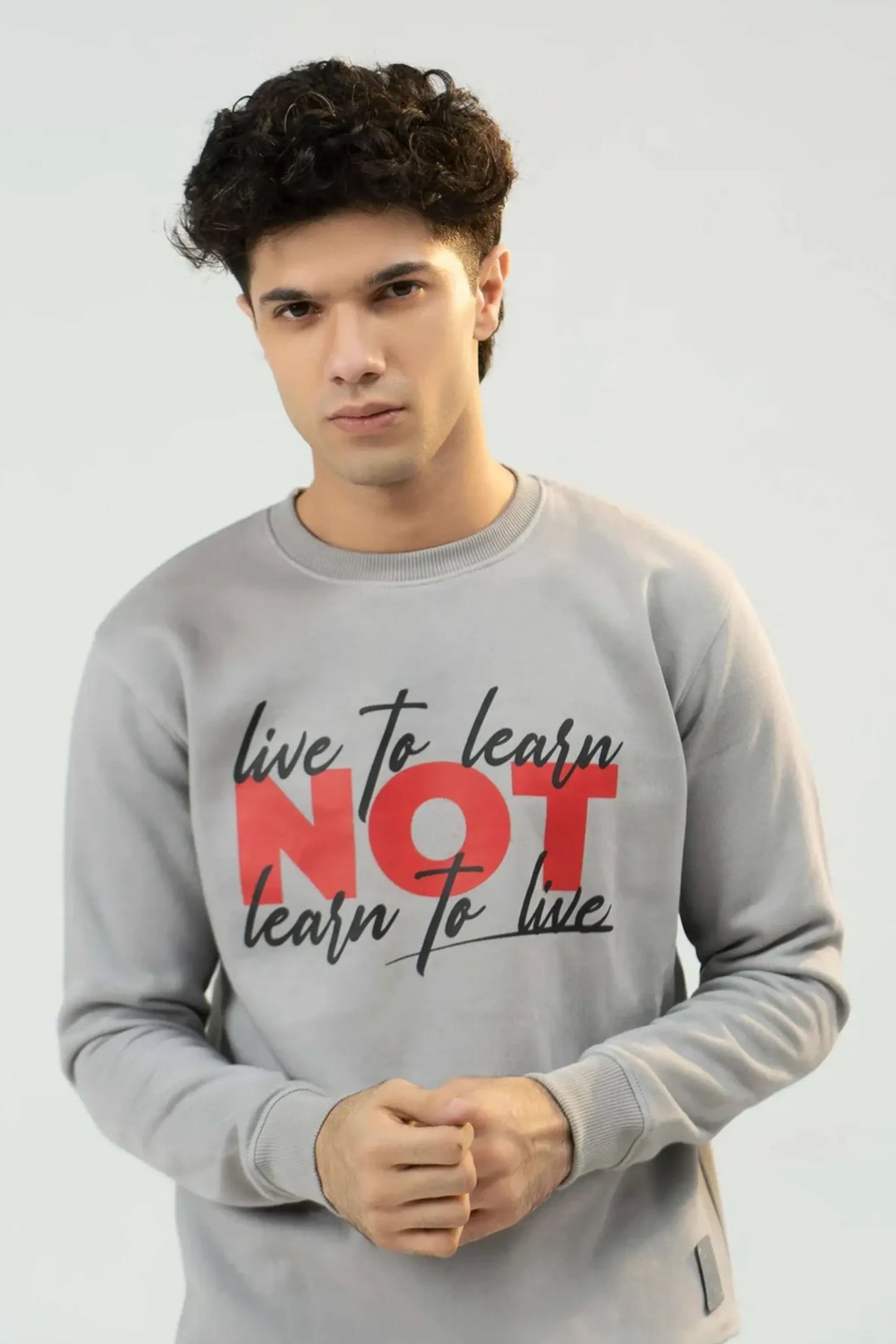 Person wearing a gray sweatshirt with motivational text on a plain background
