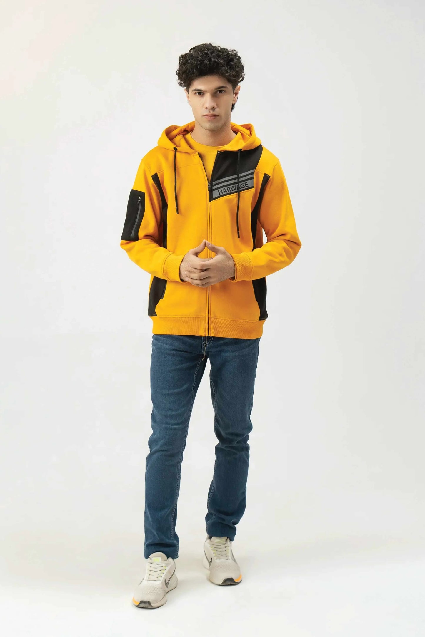 Person wearing a yellow and black hoodie with blue jeans