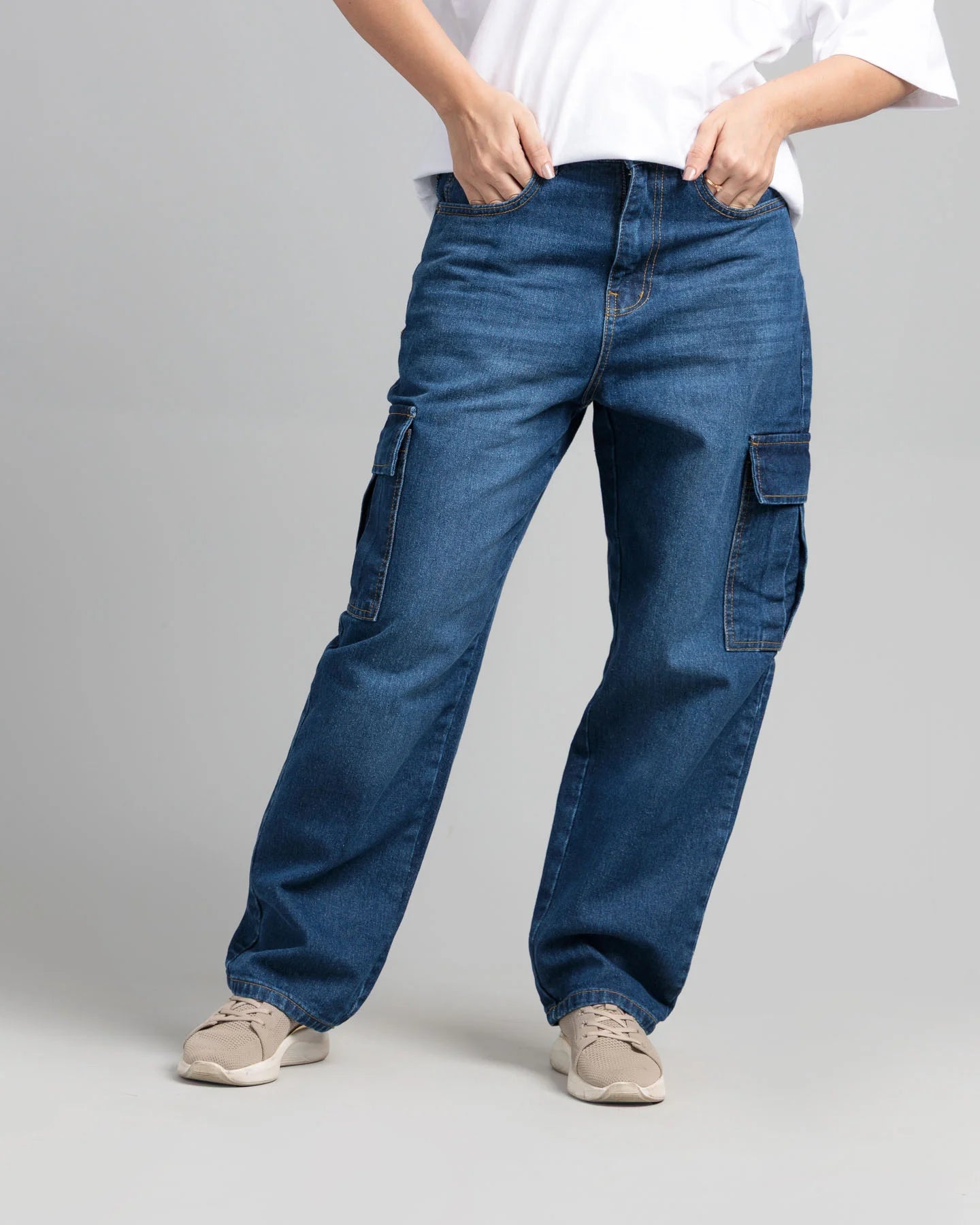 Person wearing blue cargo jeans on a gray background