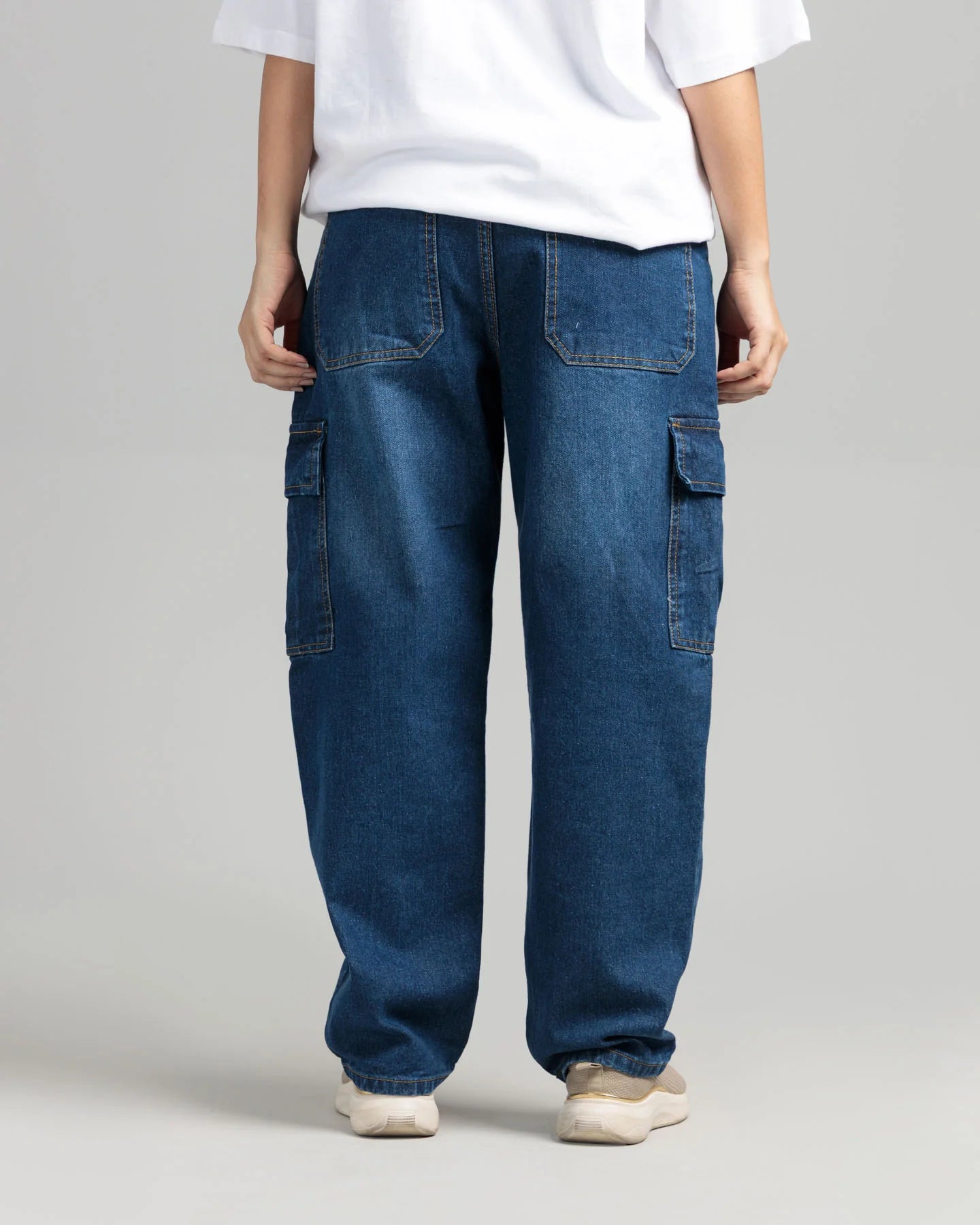 Person wearing blue cargo pants and a white shirt on a plain background