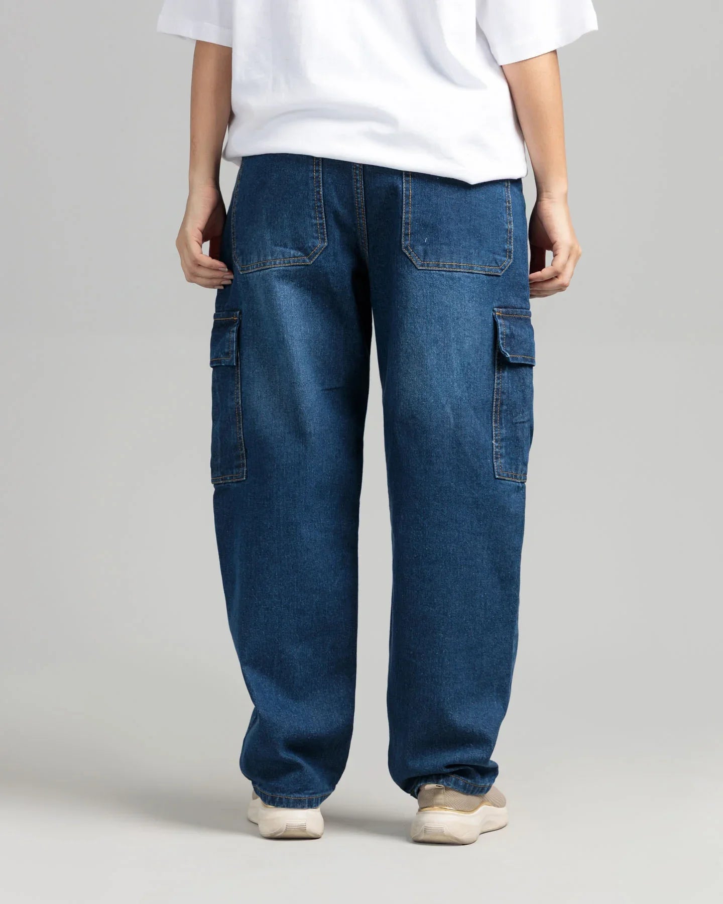 Person wearing blue cargo pants and a white shirt on a plain background
