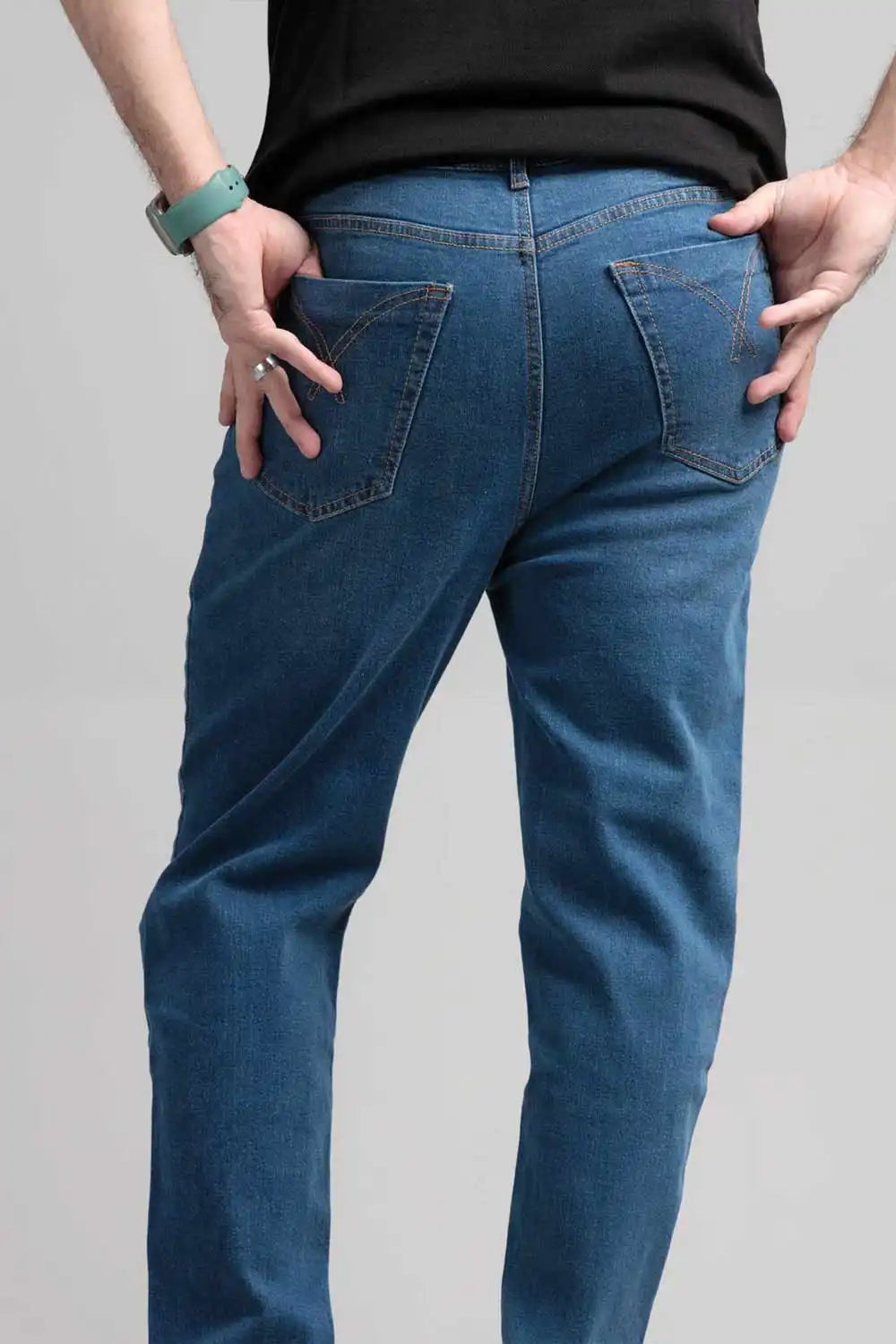 Person wearing blue jeans on a plain background