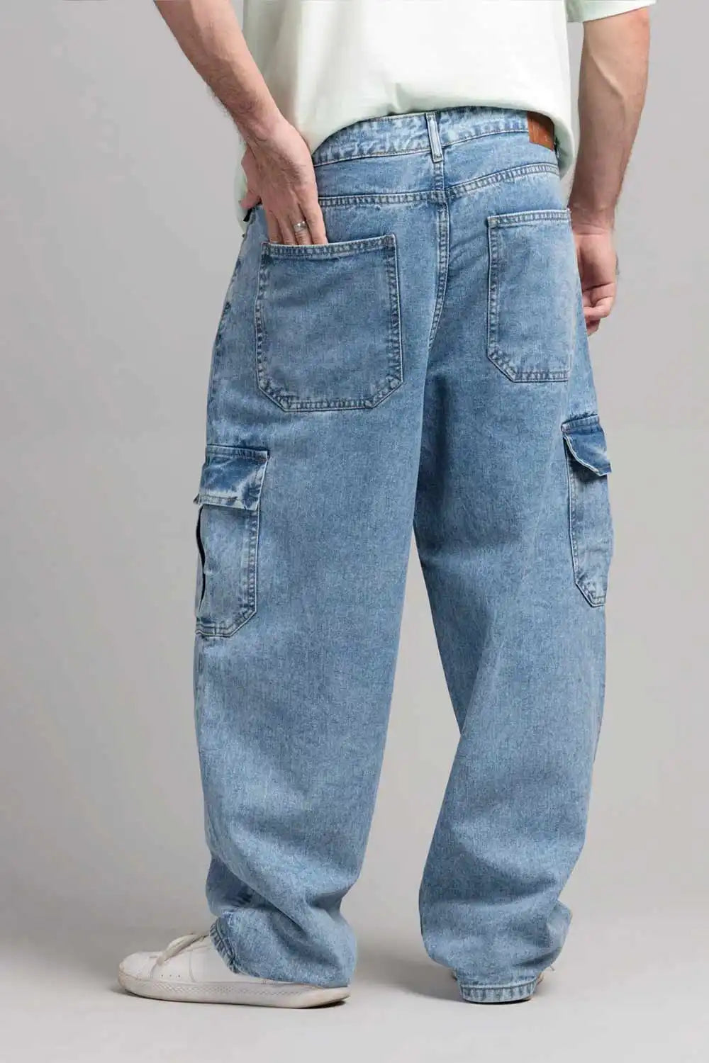 Person wearing light blue baggy jeans on a plain background