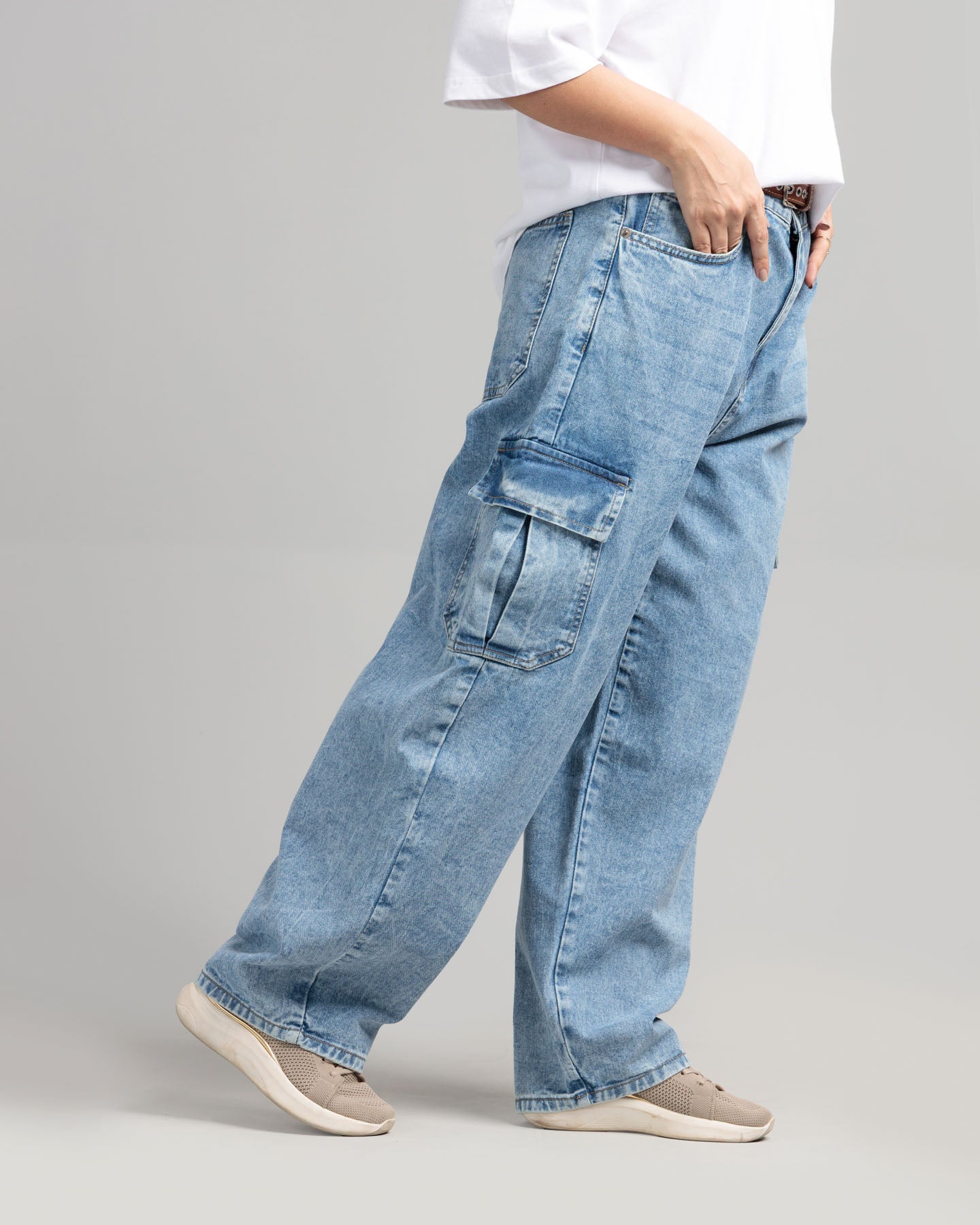 Person wearing light blue cargo jeans on a gray background