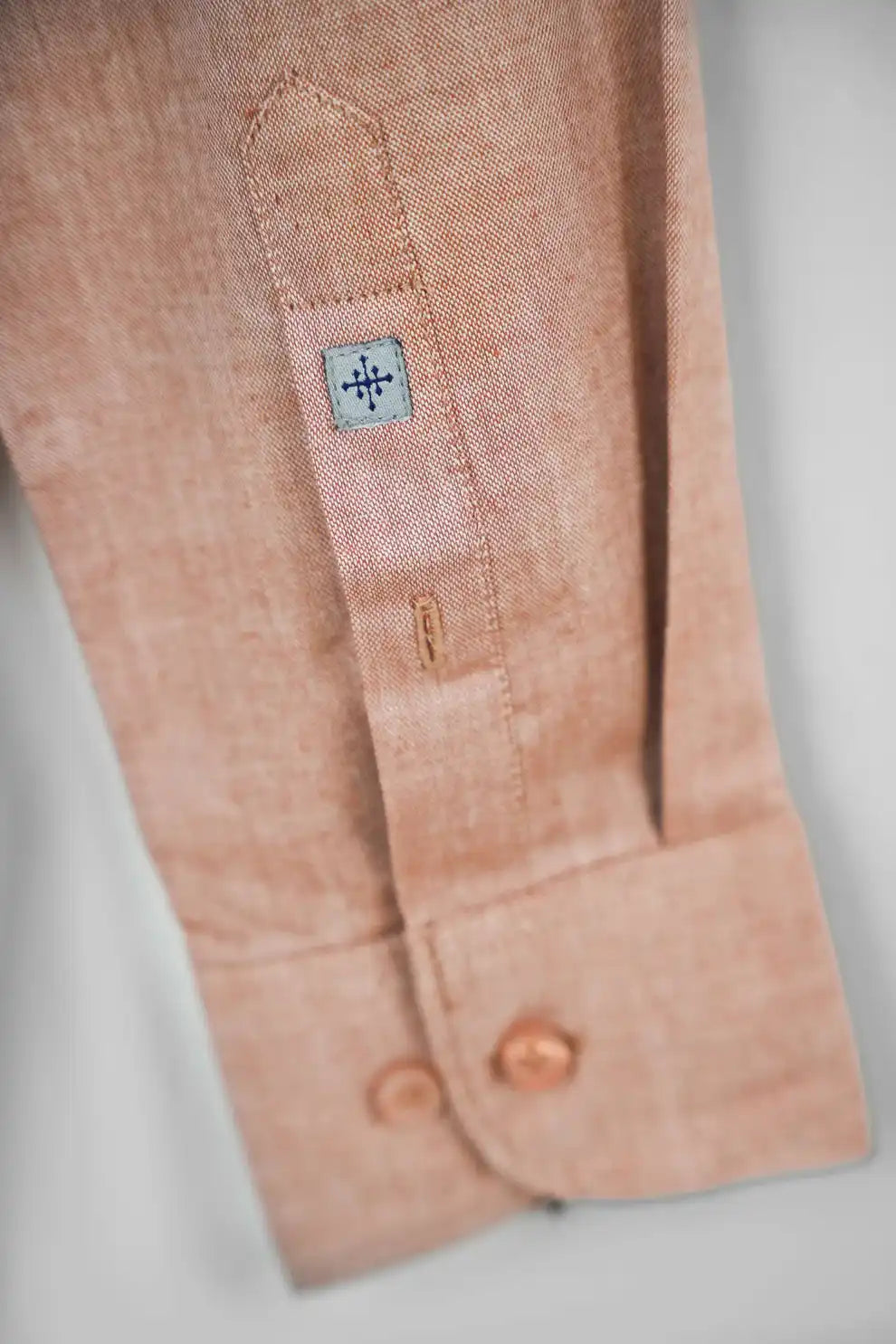 Peach shirt sleeve cuff with a brand label
