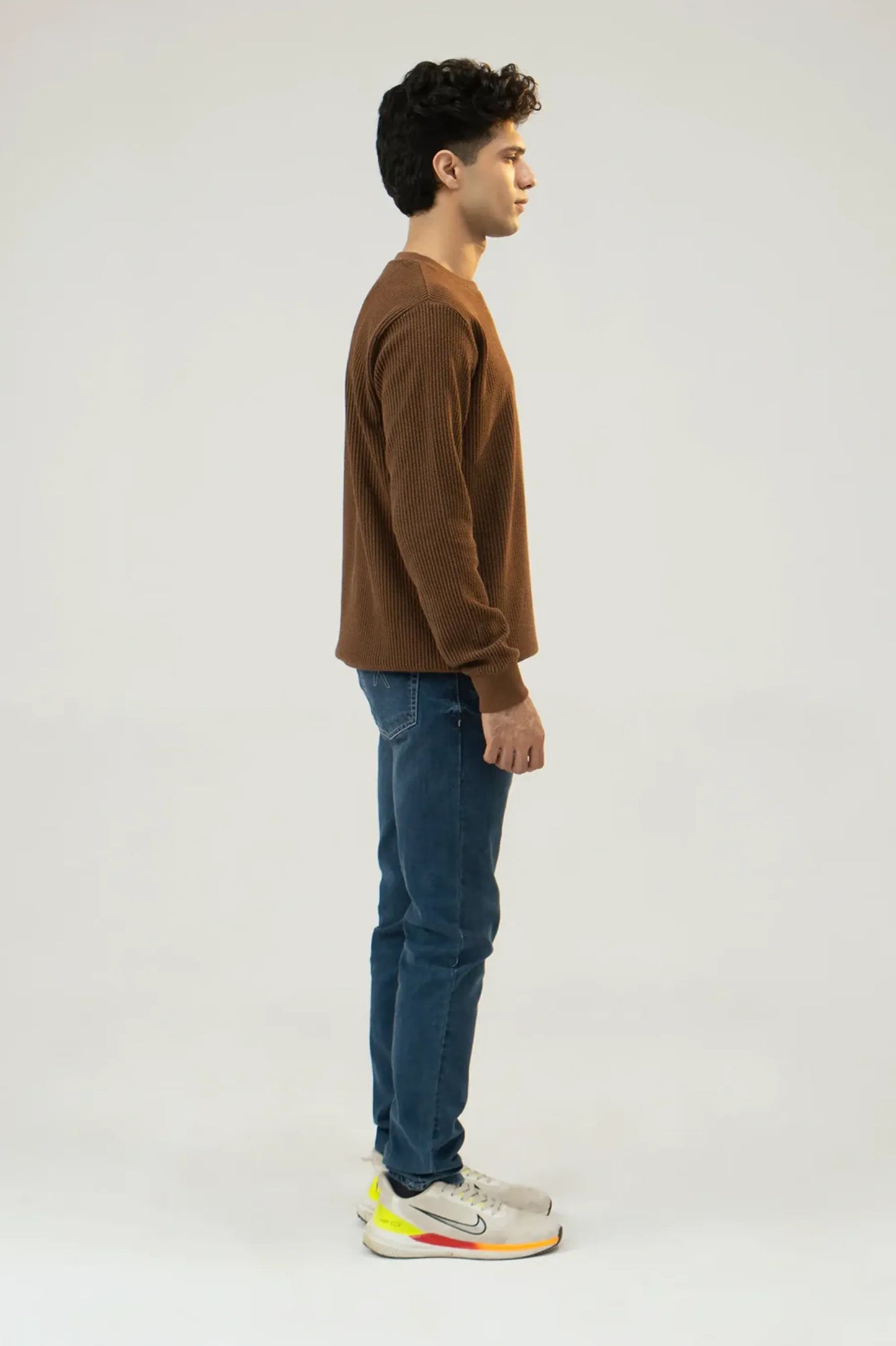 Side profile view showing sleeve and fit of brown sweatshirt
