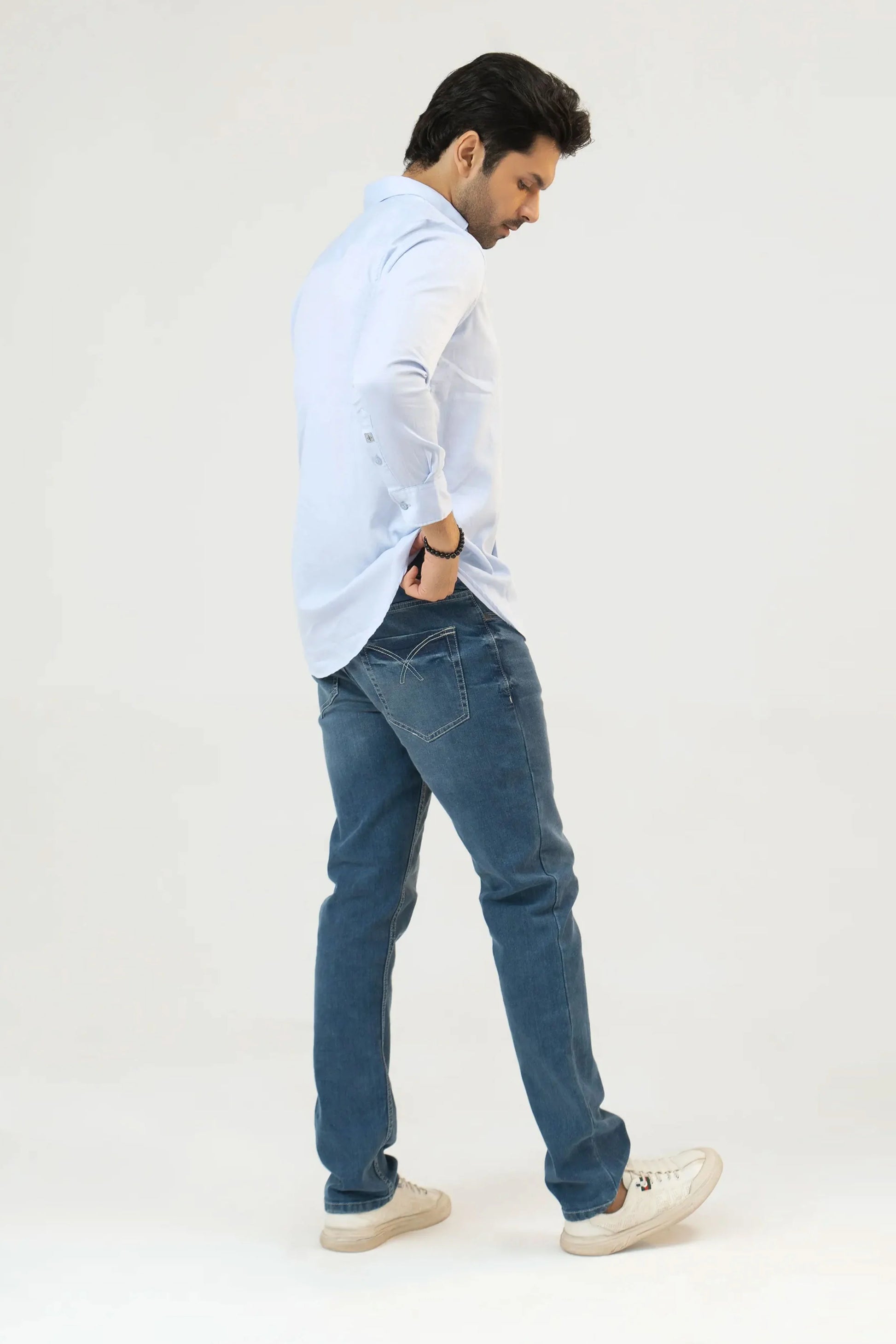 Side view of a man dressed in a light blue shirt and blue jeans