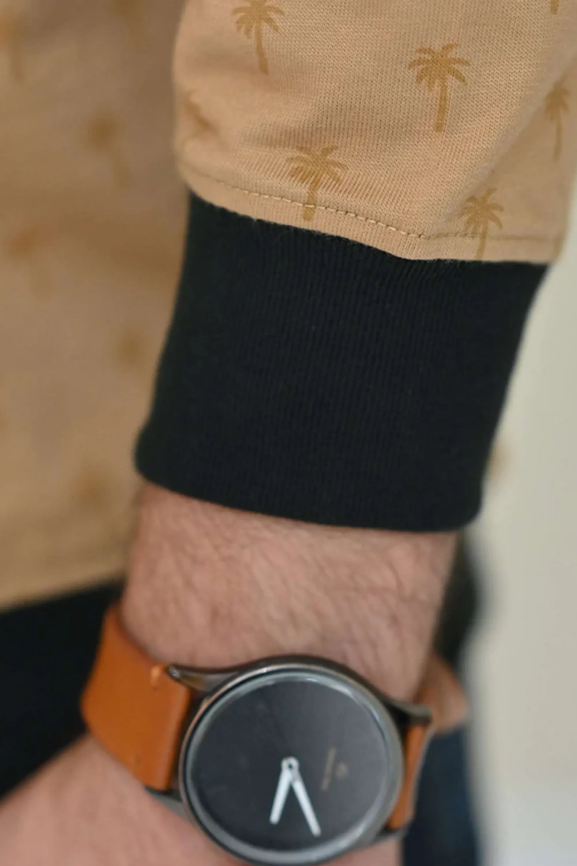 Sleeve detail with cuff finish and wristwatch on beige sweatshirt