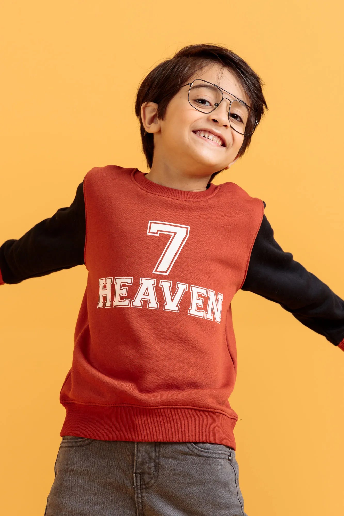 Smiling little boy jumping in orange rust sweatshirt