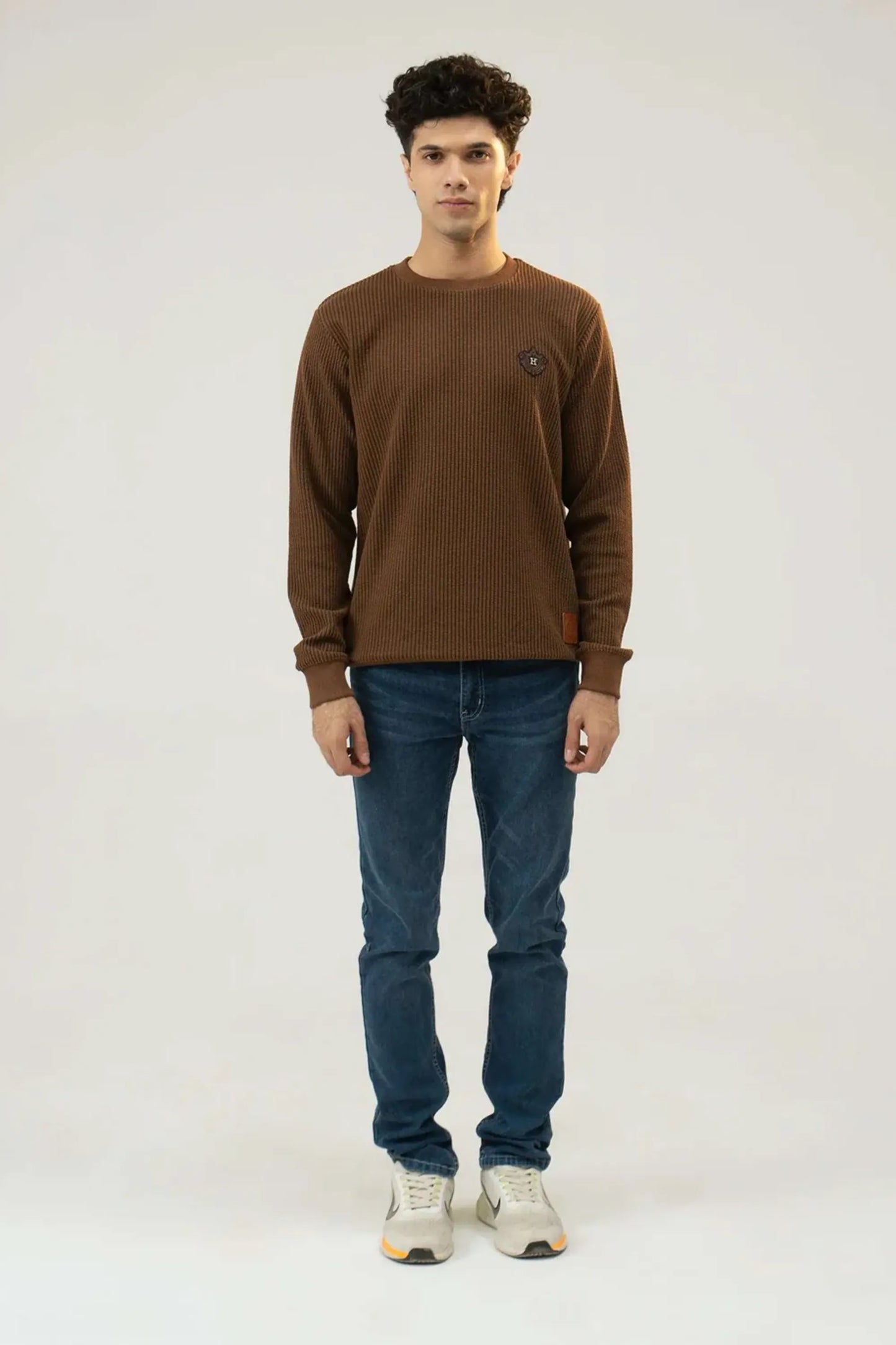 Straight standing full-length view in a brown sweatshirt and jeans