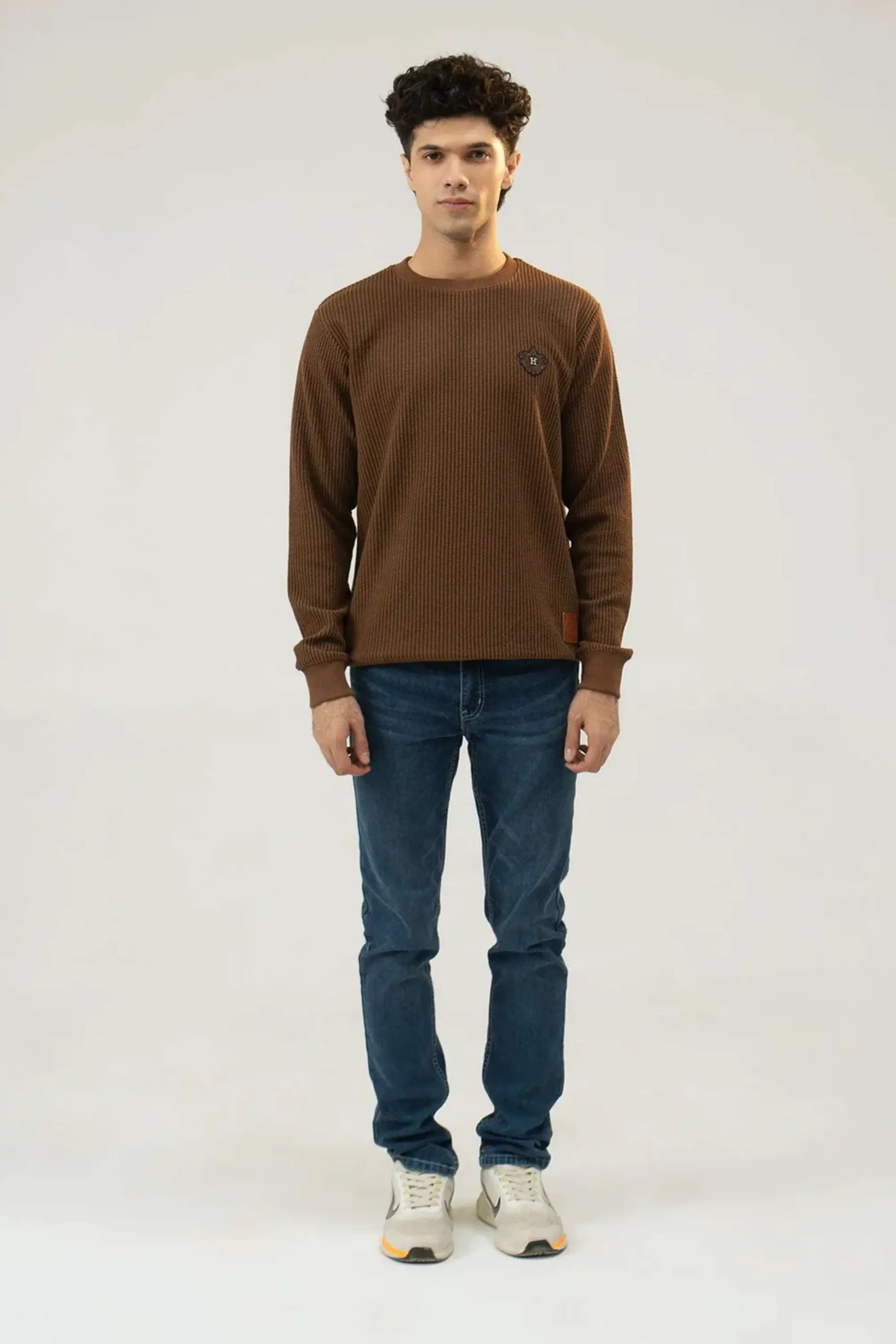 Straight standing full-length view in a brown sweatshirt and jeans