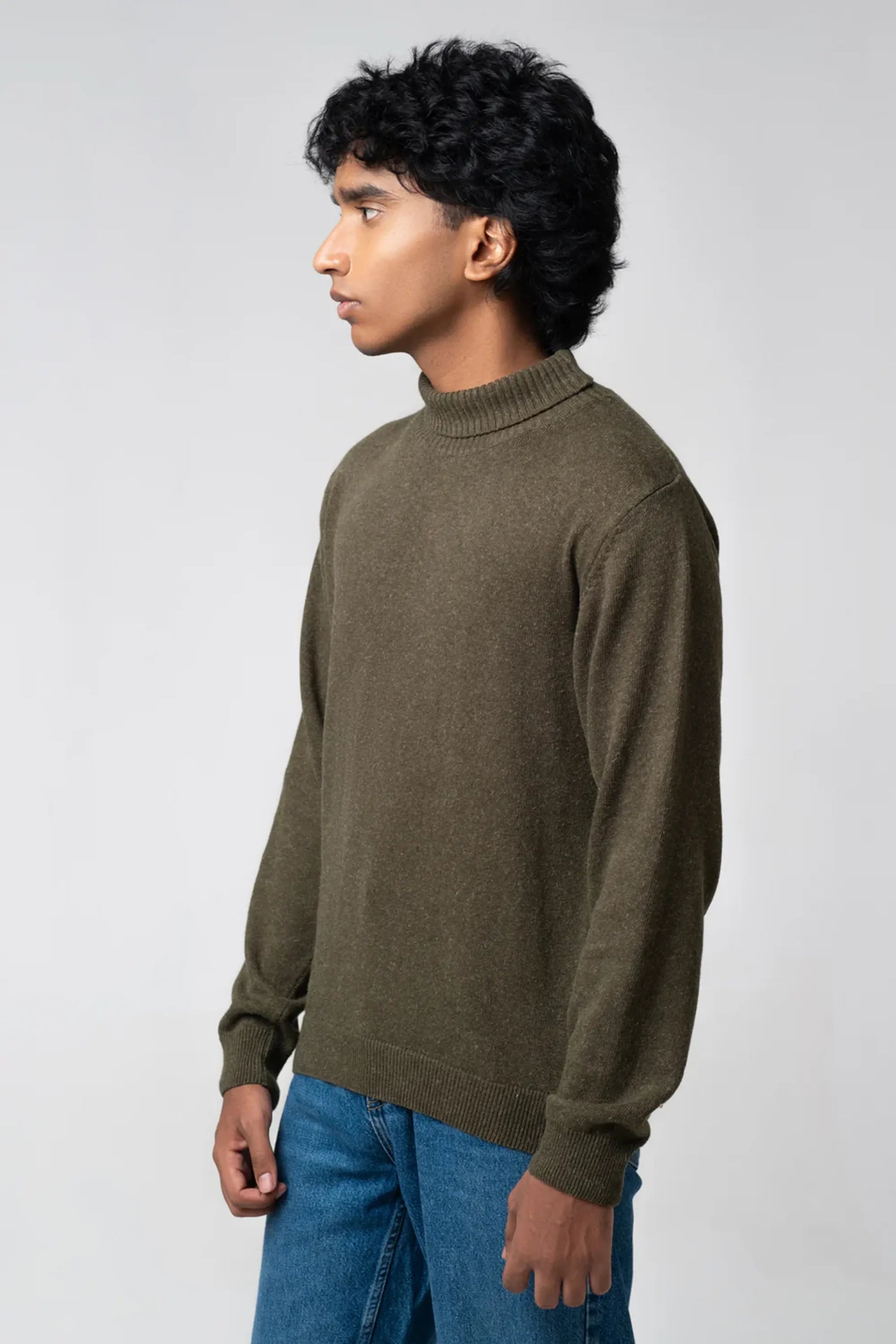 Side profile view wearing turtle neck sweater olive with denim