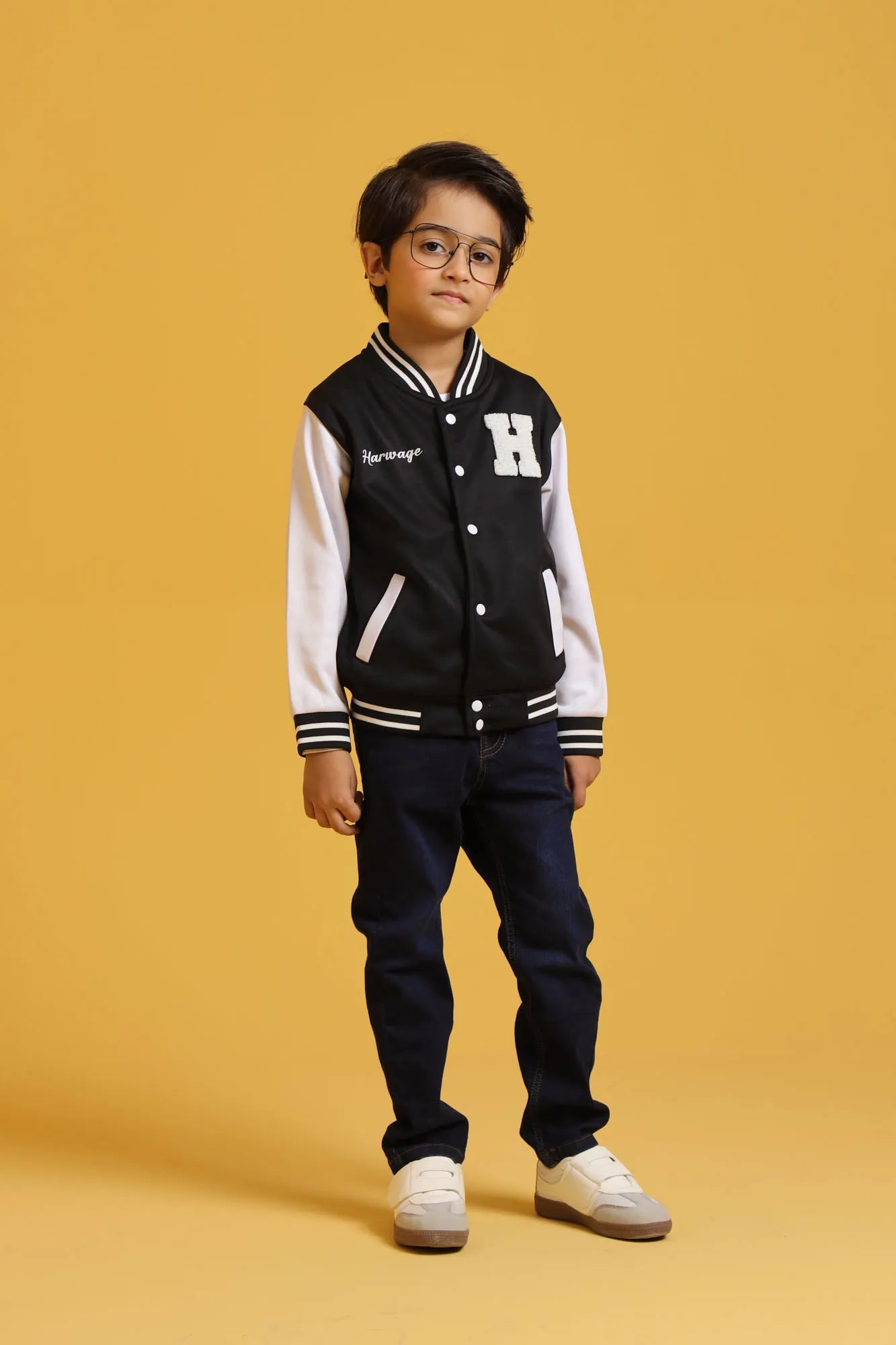 Young boy standing in black varsity jacket and dark jeans