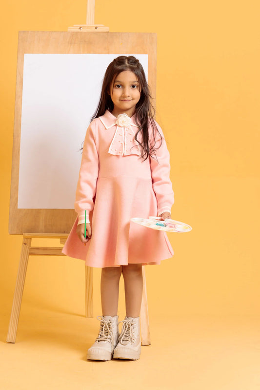 Young girl in a pink dress standing next to an easel on a yellow background